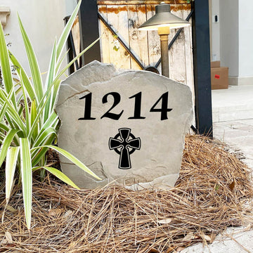 Engraved Celtic Cross Address Stone nestled among colorful flowers and greenery, combining custom house numbers with meaningful Celtic artwork. This weather-resistant address stone adds lasting beauty to walkways, patios, and landscape beds.