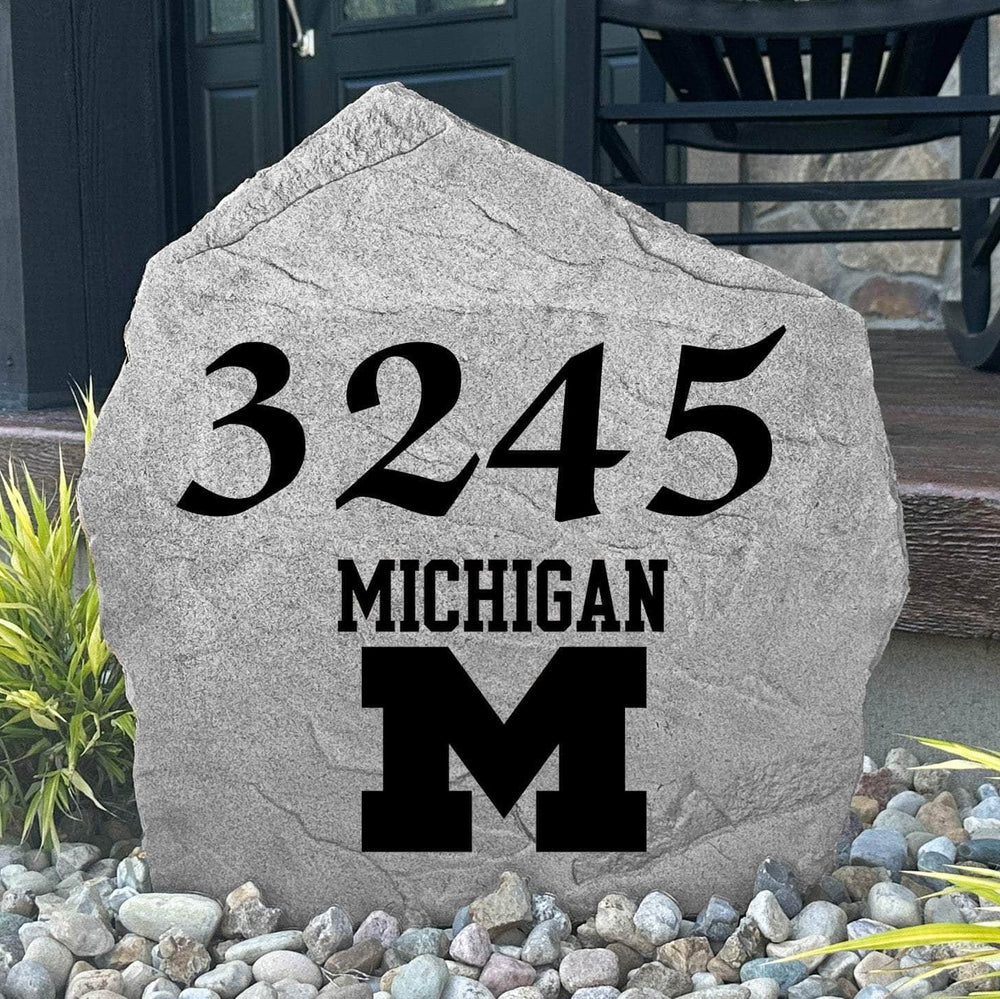Custom University of Michigan Address Stone displayed in a landscaped flower bed, showcasing personalized house numbers and officially licensed Wolverines artwork. This engraved address stone creates a beautiful focal point for alumni homes and outdoor spaces.