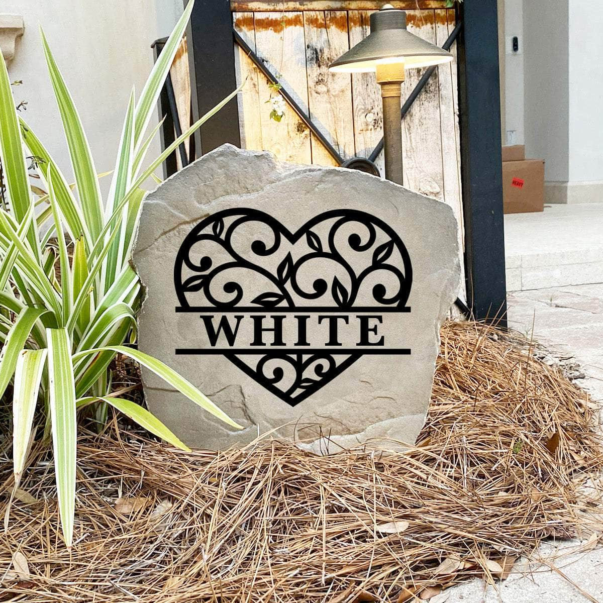 Engraved Heart Monogram Stone nestled among colorful flowers and greenery, bringing warmth and personalized charm to front yard landscapes and outdoor living spaces. Its weather-resistant design provides lasting beauty.