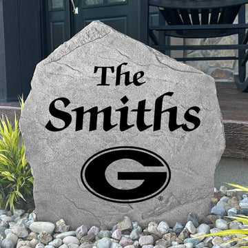 Custom University of Georgia Name Stone displayed in a landscaped flower bed, showcasing personalized family lettering and officially licensed Georgia Bulldogs artwork. This decorative outdoor stone creates a beautiful focal point for alumni homes and Bulldogs fans.
