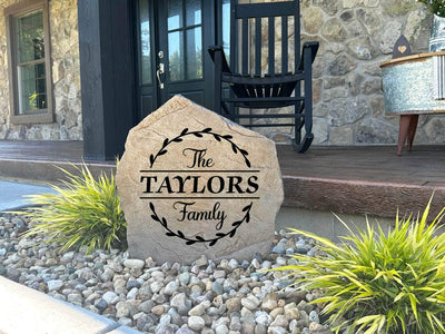 Decorative stone with family surname surrounded by vine artwork.