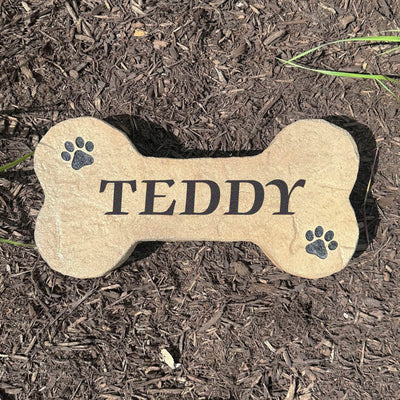 Personalized DogBone stone for pet memorial with engraved name and paw prints.