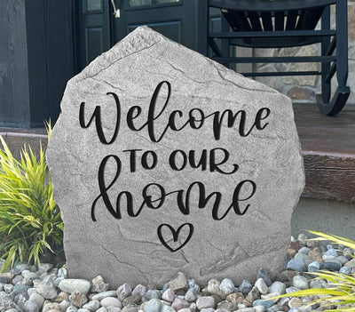 Rustic outdoor rock engraved with Welcome to Our Home and heart.