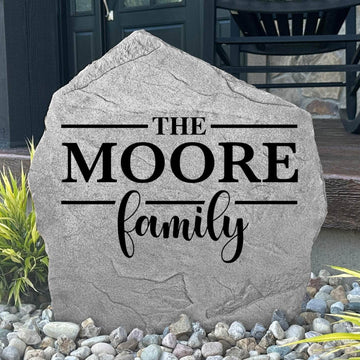 Custom Family Name Stone displayed in a landscaped flower bed, showcasing personalized engraving and elegant craftsmanship. This engraved outdoor stone creates a beautiful focal point for walkways, porches, and home entrances.