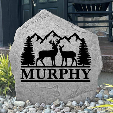 Personalized Deer Mountain Name Stone featuring custom family names and majestic deer and mountain artwork engraved directly into the stone surface. This decorative outdoor stone adds rustic charm and curb appeal to cabins, front yards, gardens, and entryways.