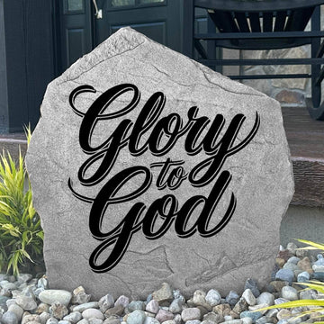 Glory To God Stone displayed in a landscaped flower bed, showcasing elegant engraving and timeless craftsmanship. This decorative outdoor stone creates a meaningful focal point for gardens and walkways.