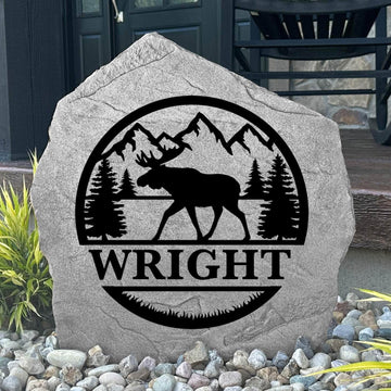 Custom Moose Monogram Stone displayed in a landscaped flower bed, showcasing personalized engraving and wildlife-inspired artwork. This engraved outdoor stone creates a beautiful focal point for cabins, gardens, and walkways.