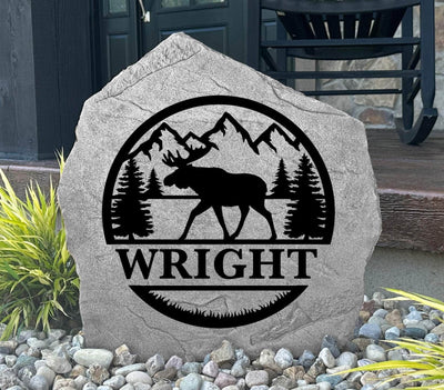 Custom engraved moose-themed garden stone with monogram and natural mountain background.
