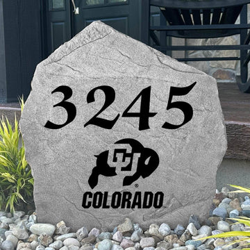 Custom University of Colorado Address Stone displayed in a landscaped flower bed with personalized house numbers and officially licensed Colorado Buffaloes artwork. This engraved address marker creates a beautiful focal point for alumni homes and devoted Buffaloes fans.
