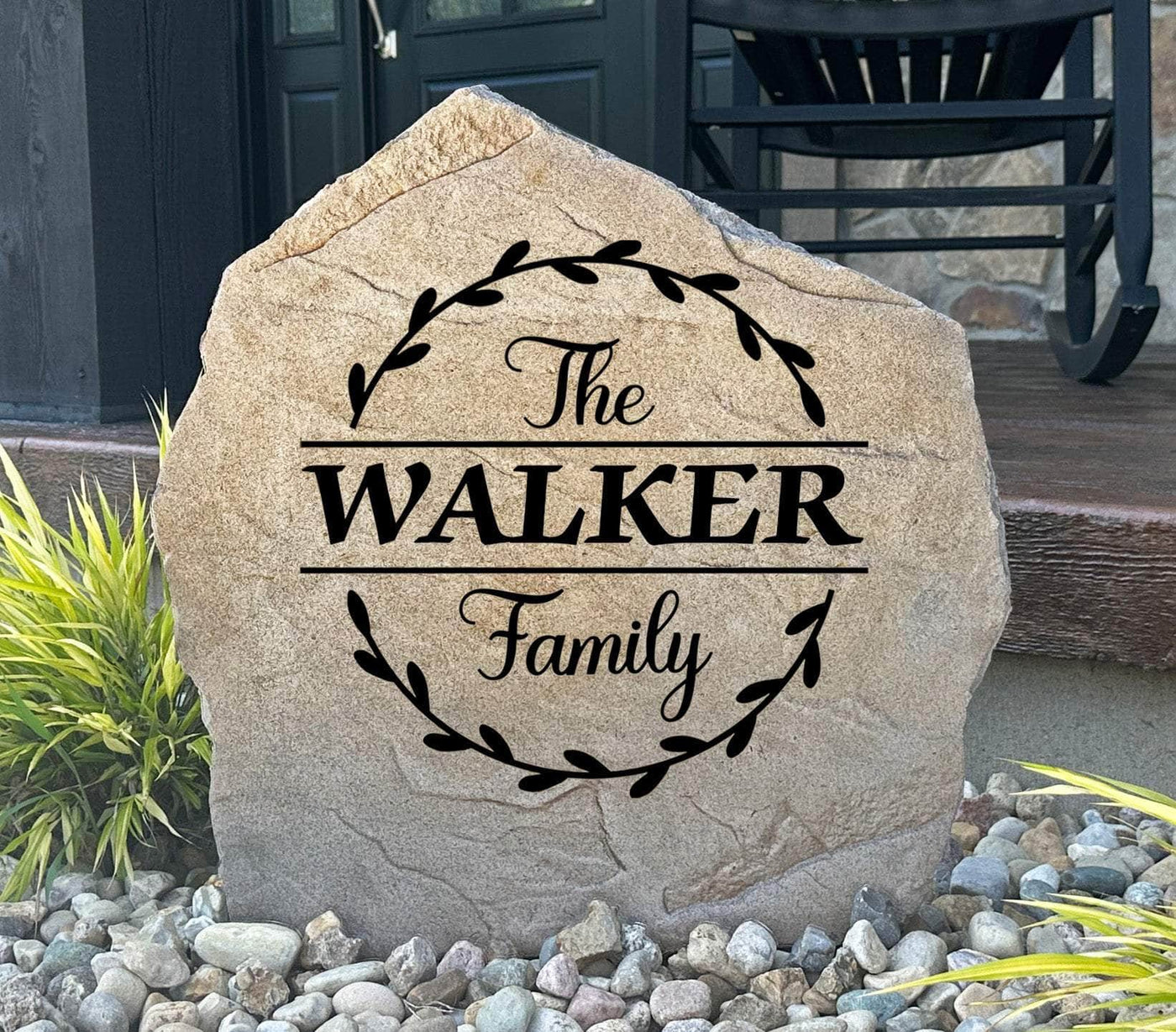 Personalized family name stone with vine circle design for outdoor display.