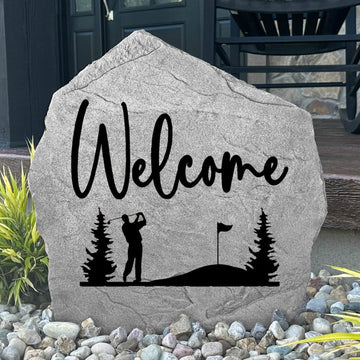Custom Welcome Golf Stone displayed in a landscaped flower bed, showcasing detailed golf artwork and a welcoming design. This engraved outdoor stone creates a beautiful focal point for walkways and home entrances.