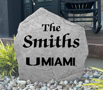 Custom University of Miami Name Stone displayed in a landscaped flower bed, showcasing personalized family lettering and officially licensed Miami Hurricanes artwork. This decorative outdoor stone creates a beautiful focal point for alumni homes and Hurricanes fans.