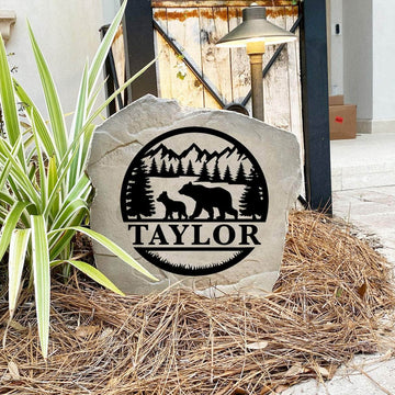 Engraved Bear Monogram Stone nestled among natural greenery and colorful flowers, bringing rustic elegance and personalized style to outdoor living spaces. Its weather-resistant design provides lasting beauty and durability.