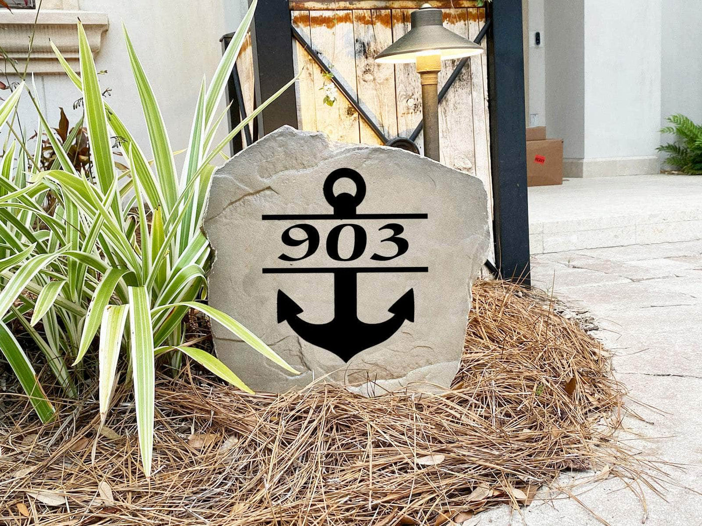 Engraved outdoor rock featuring anchor design and house address