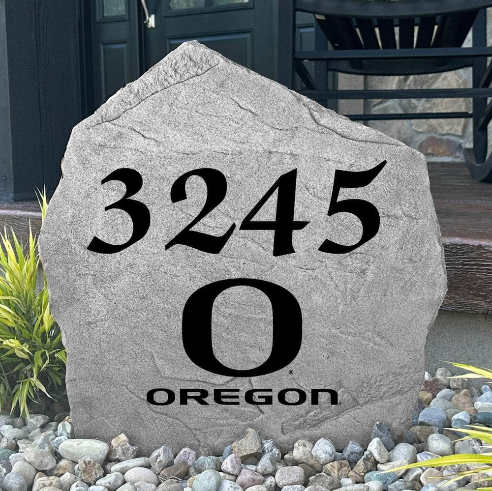 Custom University of Oregon Address Stone displayed in a landscaped flower bed, showcasing personalized house numbers and officially licensed Oregon Ducks artwork. This engraved address stone creates a beautiful focal point for alumni homes and outdoor spaces.