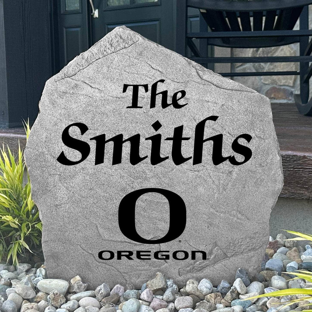Custom University of Oregon Name Stone displayed in a landscaped flower bed, showcasing personalized family lettering and officially licensed Oregon Ducks artwork. This decorative outdoor stone creates a beautiful focal point for alumni homes and Oregon fans.
