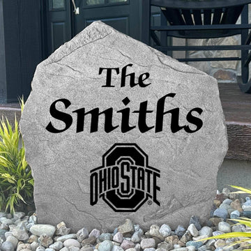 Custom Ohio State University Name Stone displayed in a landscaped flower bed, showcasing personalized family lettering and officially licensed Ohio State Buckeyes artwork. This decorative outdoor stone creates a beautiful focal point for alumni homes and Buckeyes fans.