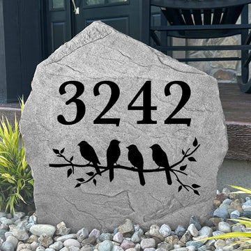 Custom Bird Address Stone displayed in a landscaped flower bed, showcasing personalized house numbers and nature-inspired bird accents. This engraved address stone creates a beautiful focal point while improving address visibility.