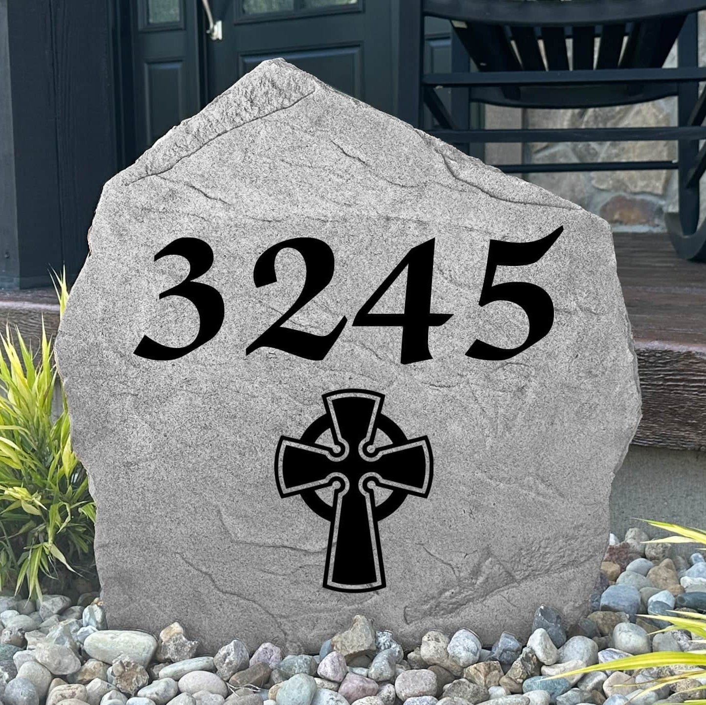 Custom Celtic Cross Address Stone displayed in a landscaped flower bed, showcasing personalized house numbers and intricate Celtic detailing engraved directly into the stone surface. This elegant address marker creates a stunning focal point for the home.