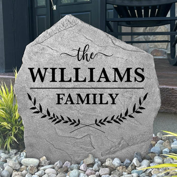 Custom Family Name Leaf Stone displayed in a landscaped garden, showcasing personalized engraving and nature-inspired leaf details. This engraved outdoor sign creates a beautiful focal point for walkways and home entrances.