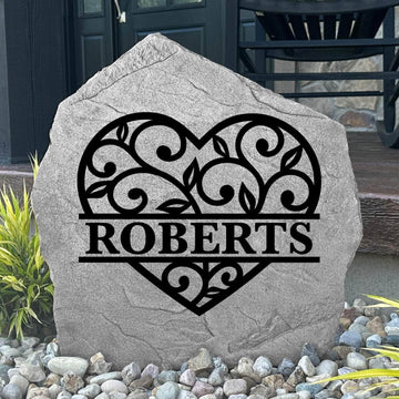 Custom Heart Monogram Stone displayed in a landscaped flower bed, showcasing personalized engraving and romantic heart accents. This engraved outdoor stone creates a beautiful focal point for walkways and home entrances.