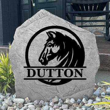 Custom Horse Monogram Name Stone displayed in a landscaped flower bed, showcasing personalized family lettering and detailed horse artwork. This engraved outdoor stone creates a beautiful focal point for horse lovers and country homes.