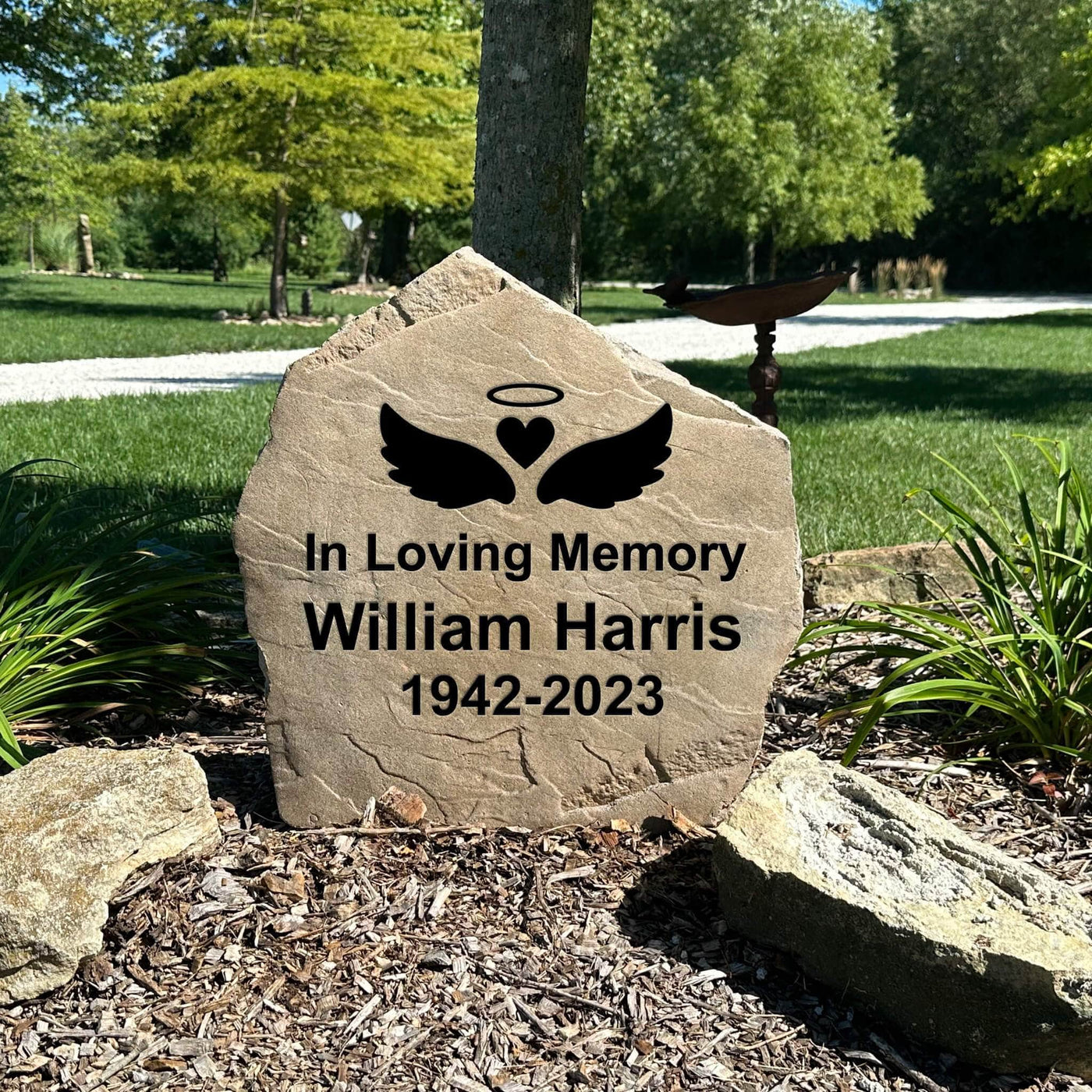 Engraved outdoor memorial stone featuring angel wings design.
