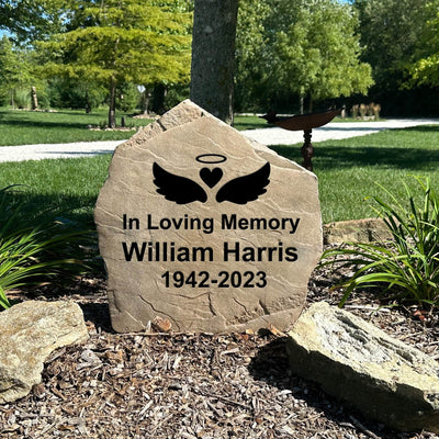 Engraved outdoor memorial stone featuring angel wings design.