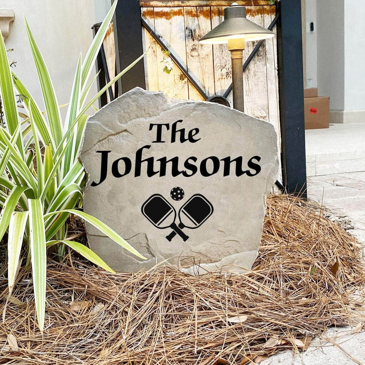 Engraved Pickleball Name Stone nestled among colorful flowers and greenery, combining custom family personalization with a love for the game. This weather-resistant decorative stone brings charm and style to patios, walkways, and landscape beds