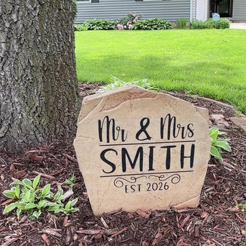 Engraved Mr. & Mrs. Name Stone nestled among colorful flowers and greenery, bringing charm and sophistication to front yard landscaping. This weather-resistant outdoor stone provides lasting beauty for patios and walkways.