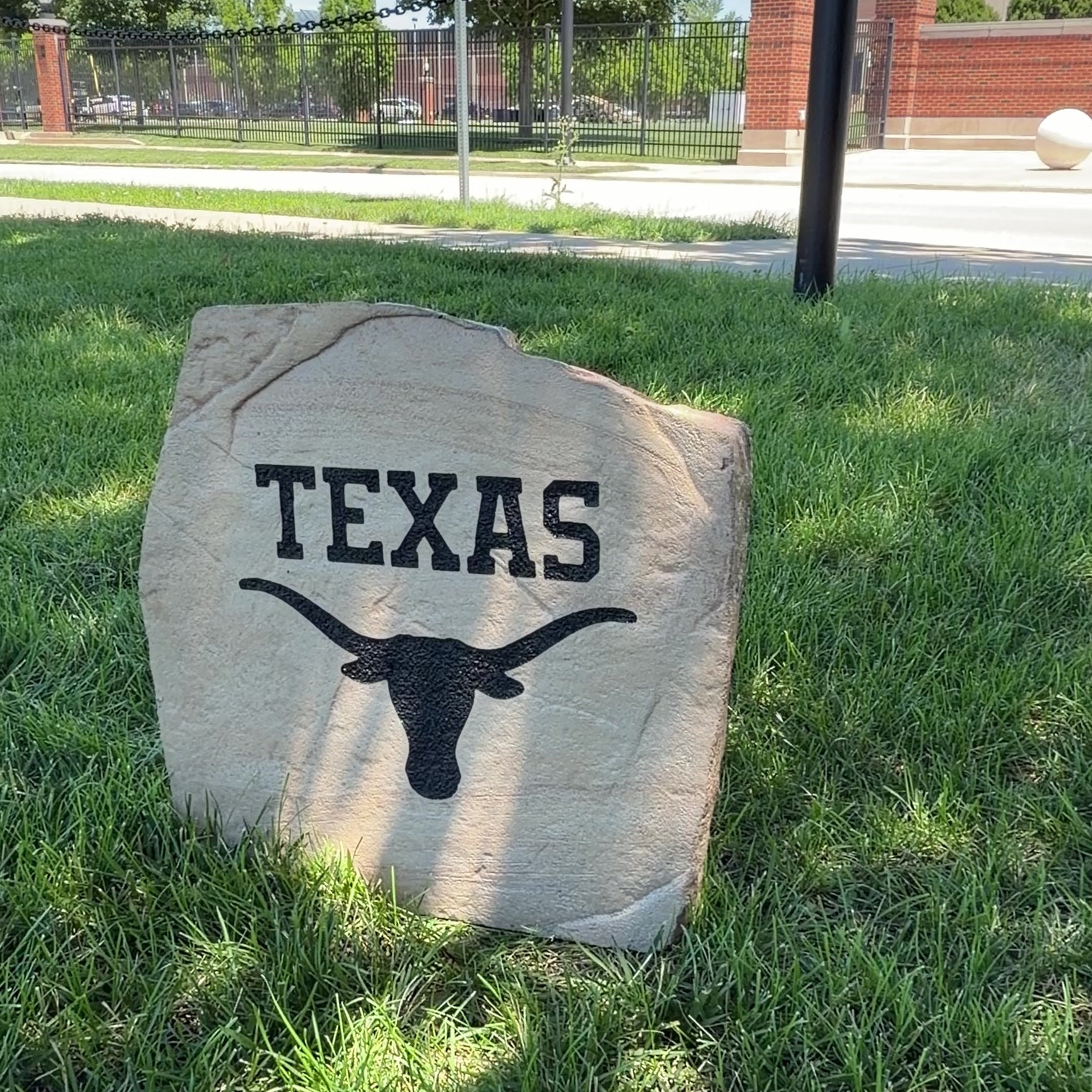 Custom Texas Longhorns Logo Stone displayed in a landscaped flower bed, showcasing officially licensed Texas Longhorns team artwork permanently engraved into the stone. This outdoor accent creates a bold focal point for Longhorns fans and outdoor living spaces.