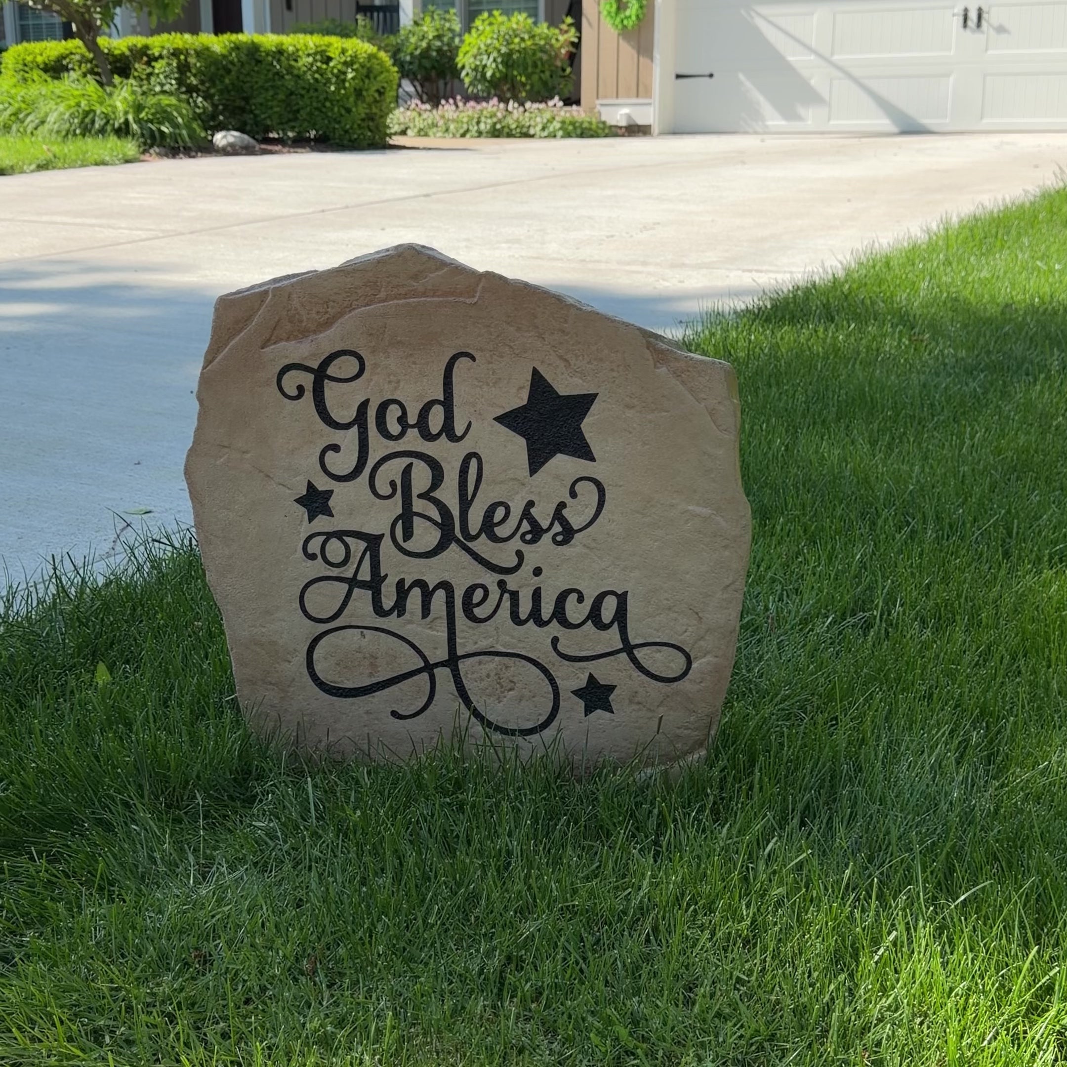 Patriotic God Bless America Stone nestled among colorful flowers and greenery, bringing faith, freedom, and classic American style to front yard landscapes and outdoor living spaces.