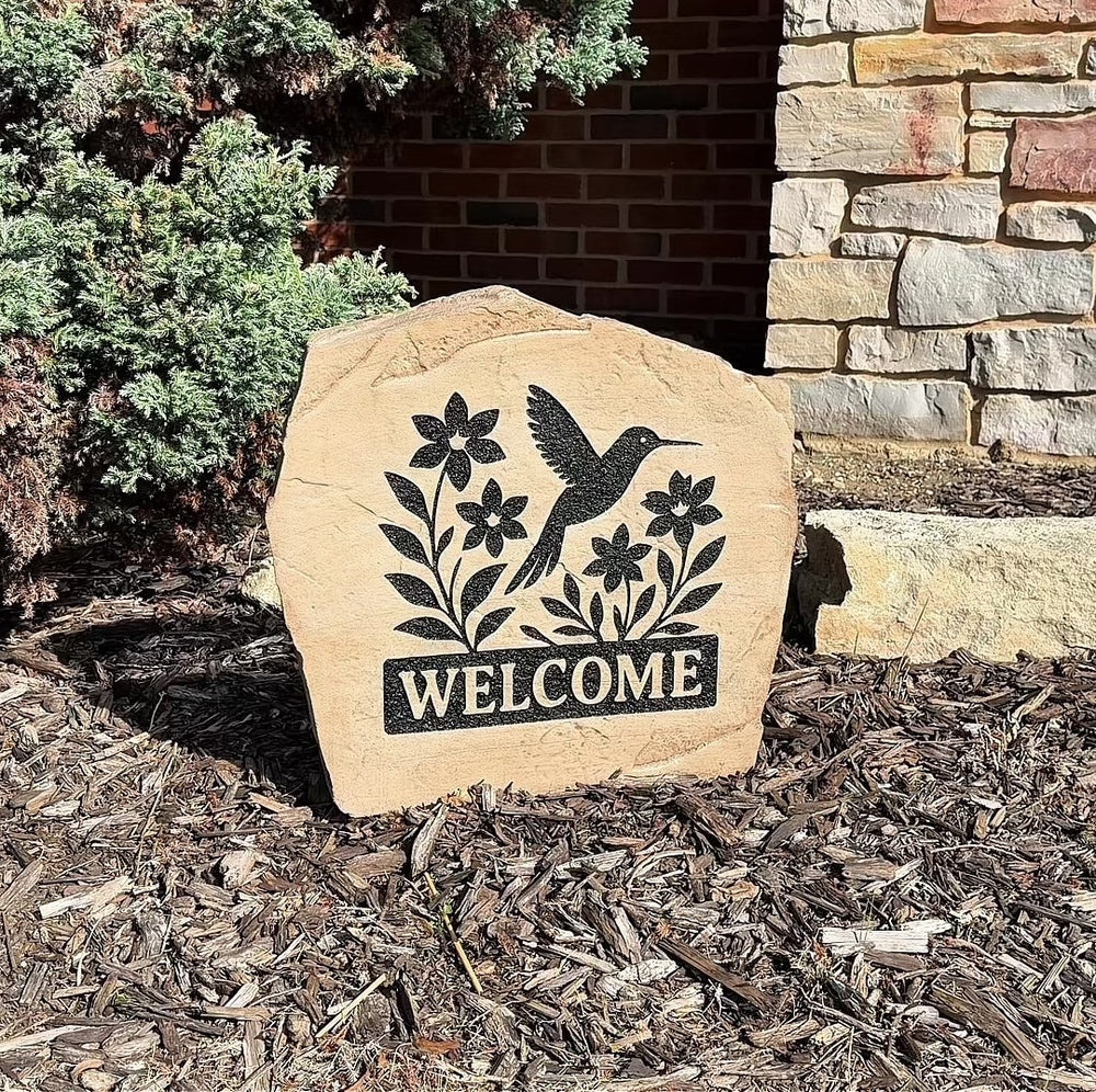 Custom Welcome Hummingbird Stone displayed in a landscaped garden, showcasing detailed hummingbird artwork and a warm welcome message. This engraved outdoor stone creates a beautiful focal point for walkways and home entrances.