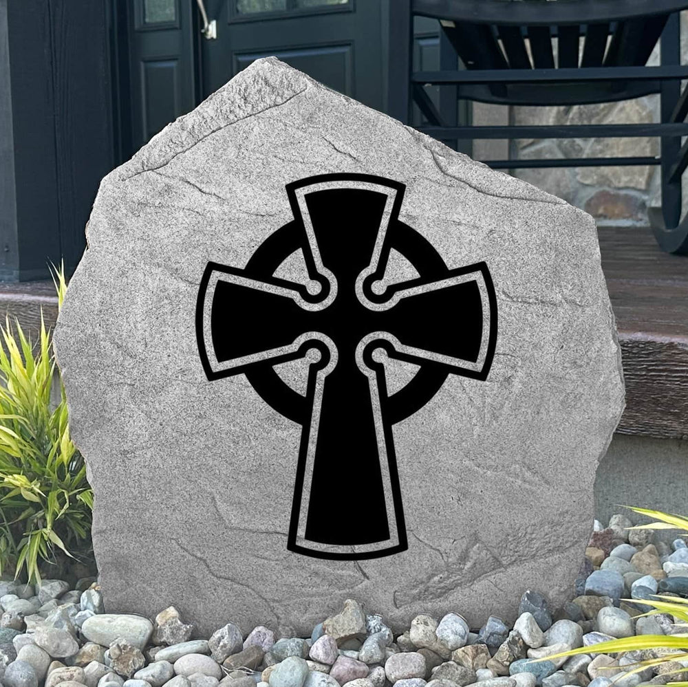 Decorative Celtic Cross Stone displayed in a landscaped flower bed, showcasing intricate Celtic artwork and lasting craftsmanship. This outdoor stone creates a peaceful focal point for walkways, gardens, and entryways.