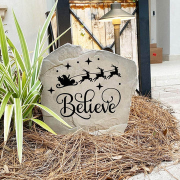 Decorative Believe Christmas Stone nestled among seasonal greenery and winter accents, bringing joy and inspiration to front yard landscapes and holiday displays. Its weather-resistant design provides lasting beauty throughout the season.