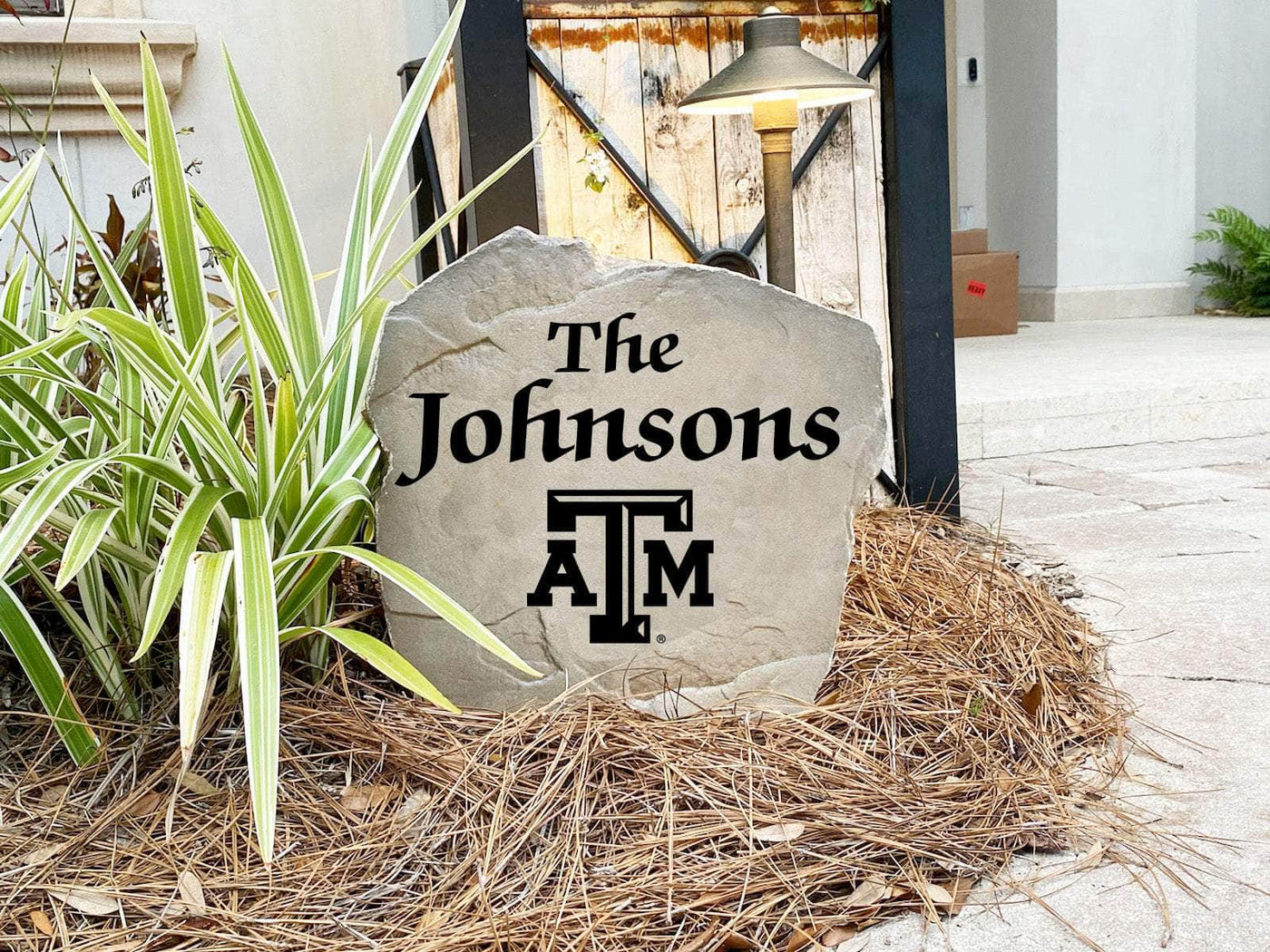 Engraved name stone with Texas A&M logo in landscaping