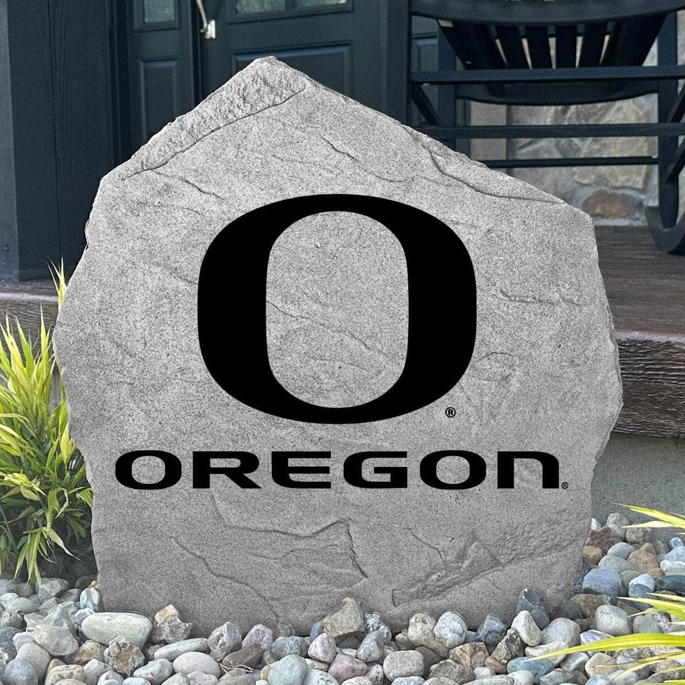 Custom Oregon Ducks Logo Stone displayed in a landscaped flower bed, showcasing officially licensed team artwork permanently engraved into the stone. This outdoor accent creates a striking focal point for alumni homes and devoted Oregon fans.