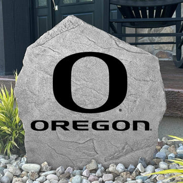 Custom Oregon Ducks Logo Stone displayed in a landscaped flower bed, showcasing officially licensed team artwork permanently engraved into the stone. This outdoor accent creates a striking focal point for alumni homes and devoted Oregon fans.