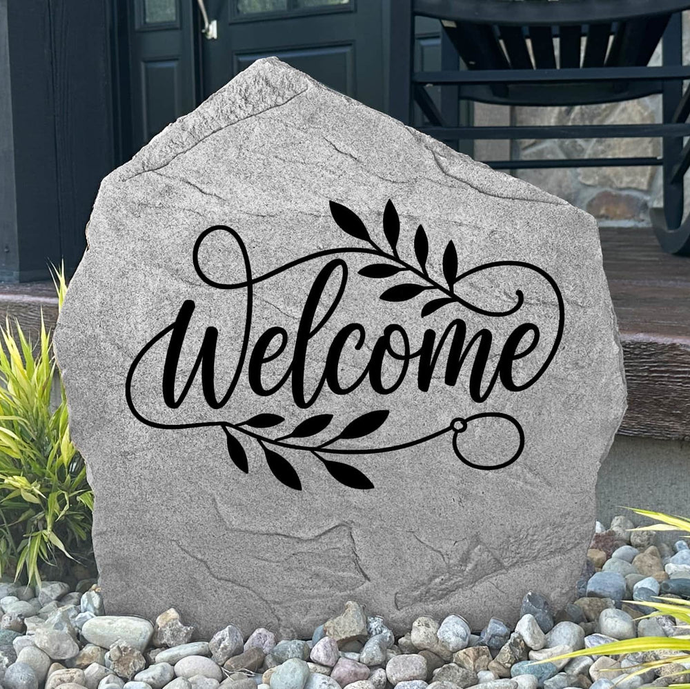 Custom Welcome Stone displayed in a landscaped flower bed, featuring permanent engraving and elegant design details. This decorative garden stone creates a warm entrance and enhances the beauty of outdoor living spaces.