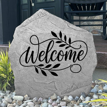 Custom Welcome Stone displayed in a landscaped flower bed, featuring permanent engraving and elegant design details. This decorative garden stone creates a warm entrance and enhances the beauty of outdoor living spaces.