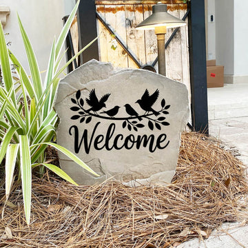 Decorative Welcome Bird Stone nestled among colorful flowers and greenery, bringing nature-inspired beauty to the landscape. The permanent engraving provides lasting durability and timeless style for any outdoor space.
