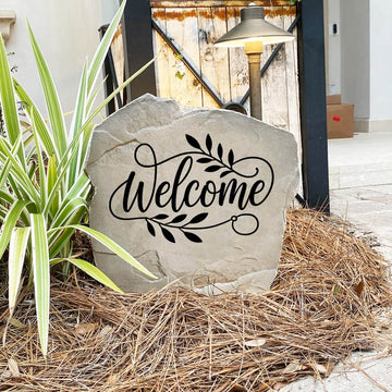 Engraved Welcome Stone nestled among colorful flowers and greenery, providing a charming focal point for walkways and front porches. This weather-resistant garden stone brings lasting style and inviting curb appeal to the home.