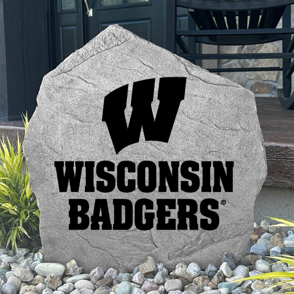 Custom University of Wisconsin Logo Stone displayed in a landscaped flower bed, showcasing officially licensed Wisconsin Badgers artwork with permanent engraving. This decorative outdoor stone creates a beautiful focal point for alumni homes and Badger fans.