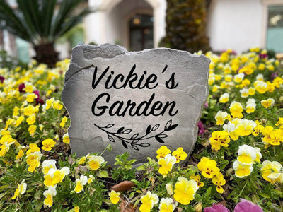 Outdoor landscaping stone with personalized family name and floral design.